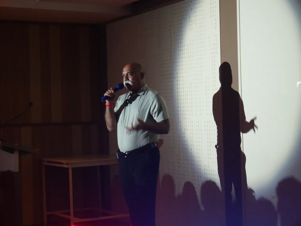 A speaker addressing the audience under a spotlight